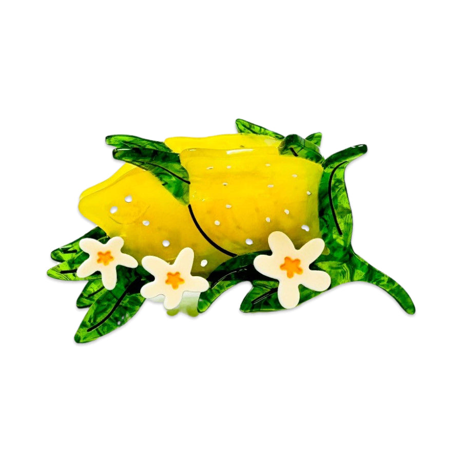 Decorative hair clip with a yellow lemon, green leaves, and white flowers on a white background