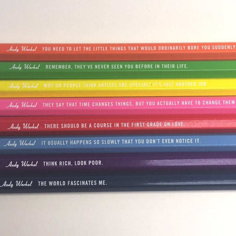 Stack of colorful books with Andy Warhol quotes on a white background