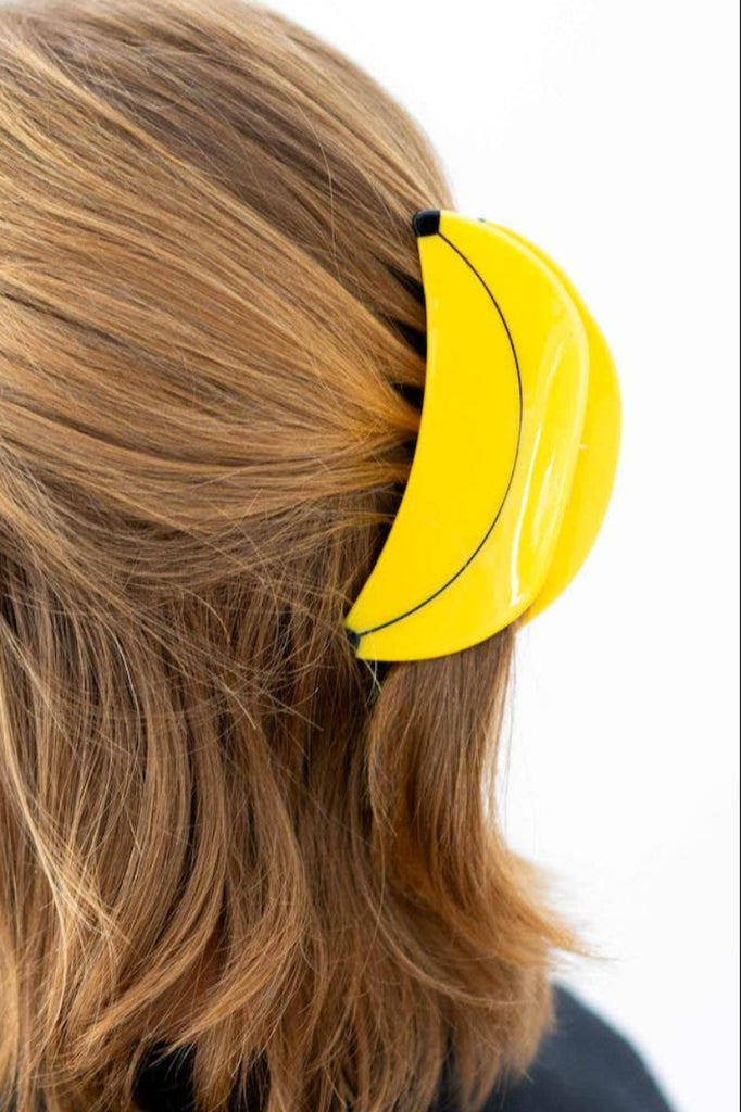 Person with a yellow banana-shaped hair clip in their hair on a white background