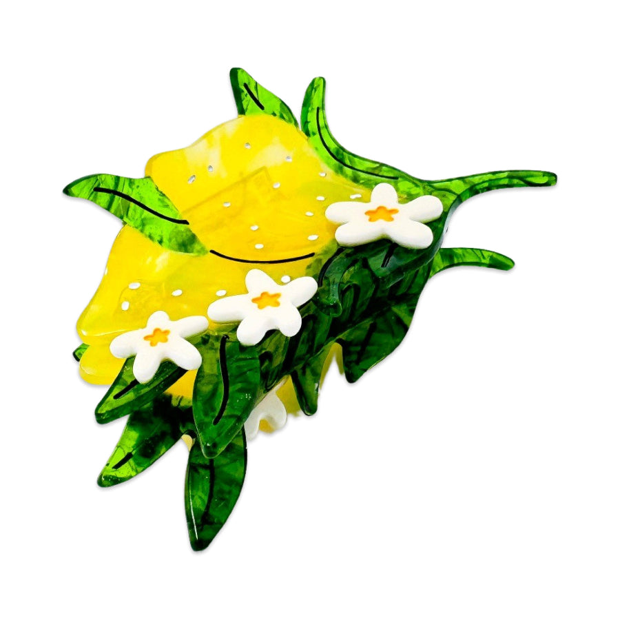 Yellow lemon hair clip with green leaves and white flowers on a white background