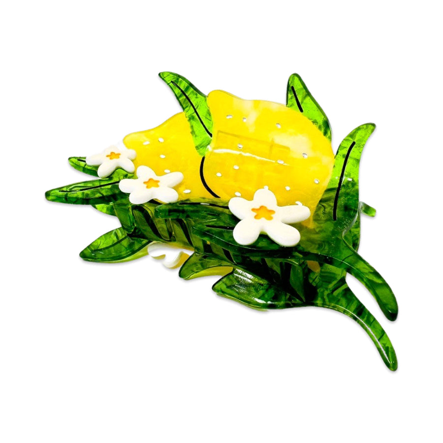 Decorative yellow lemon hair clip with white flowers and green leaves on a white background