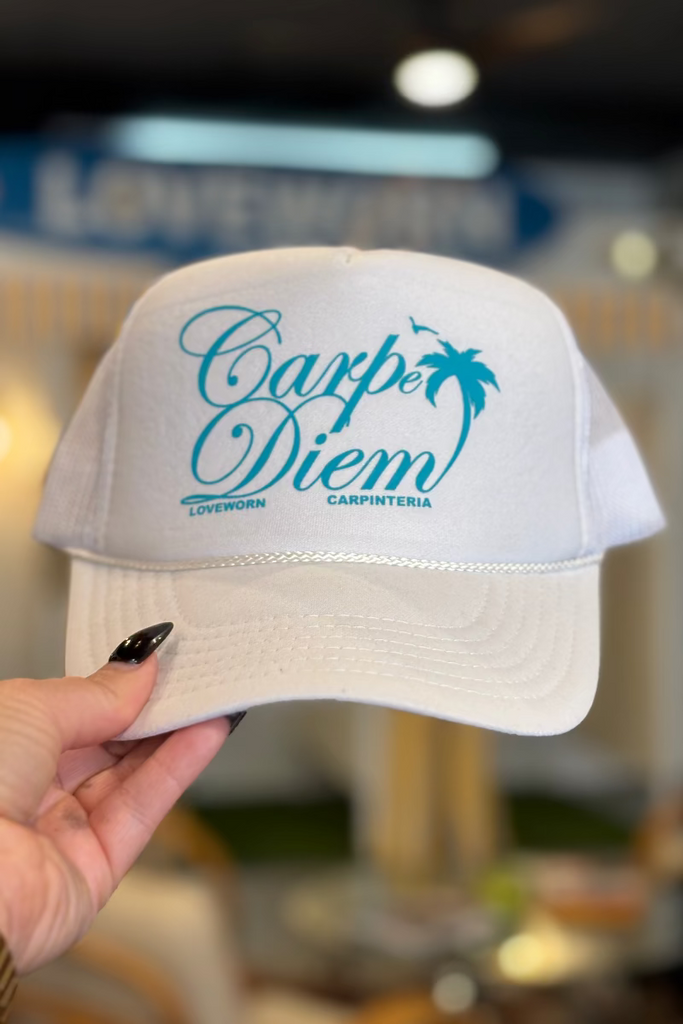 White cap with blue text held by a hand in an indoor setting