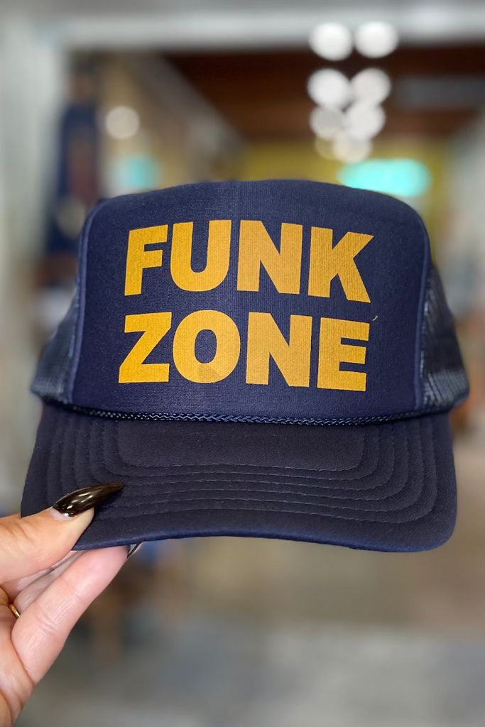 Navy blue cap with 'FUNK ZONE' in gold letters held by a hand.