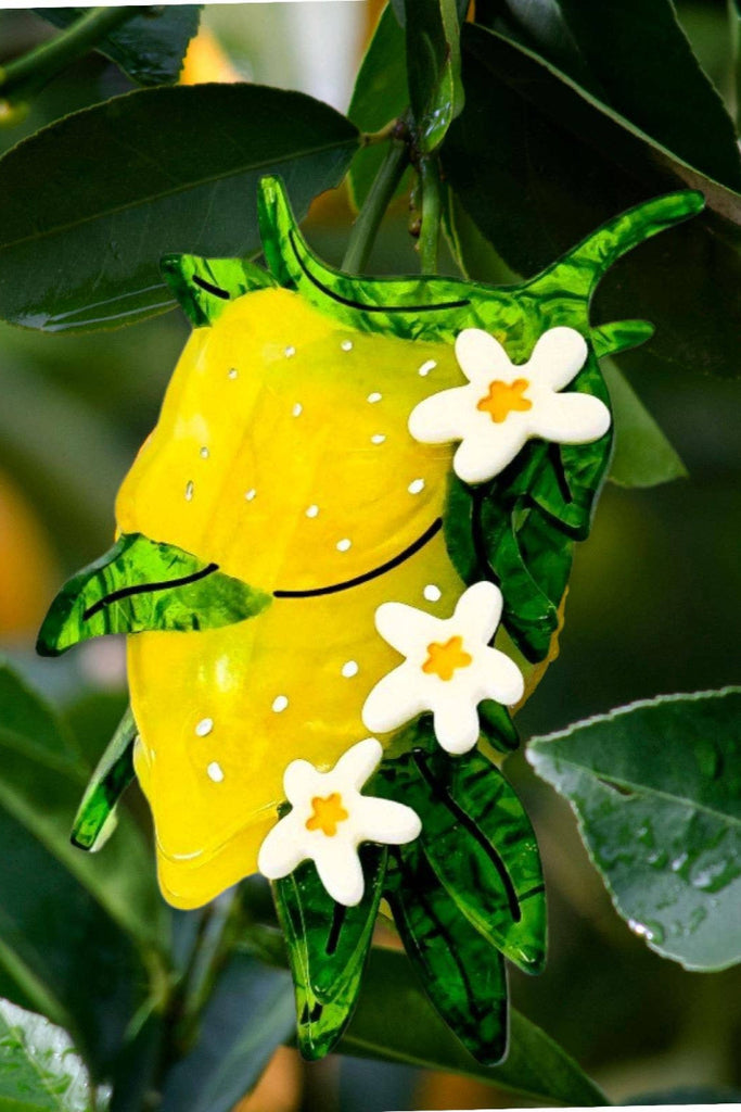 Decorative lemon with flowers and green leaves on a blurred background of oranges and leaves.