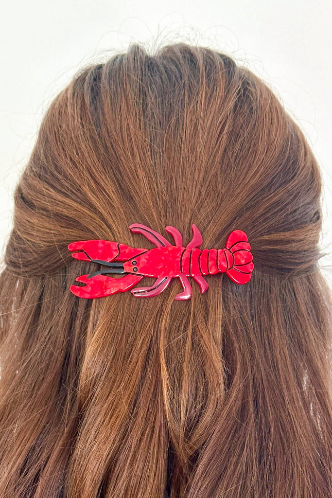 Red lobster hair clip on a person's hair against a white background
