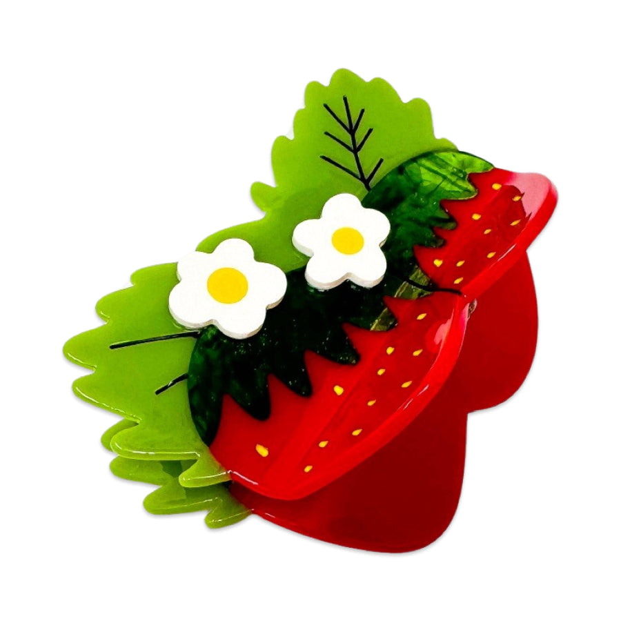 Red strawberry-shaped hair clip with green leaves and white flowers on a white background
