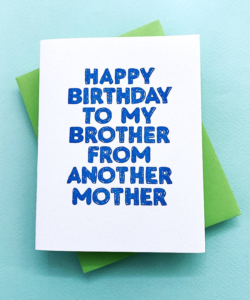 Birthday card with blue text on a white background, placed on a light blue surface.