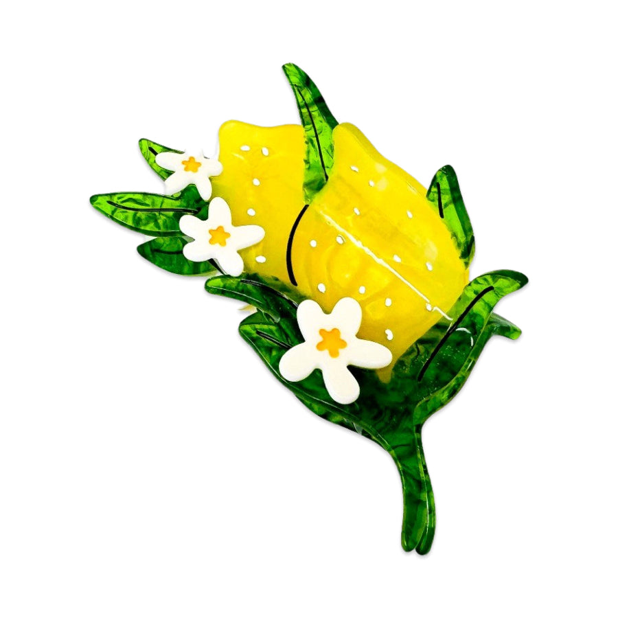 Decorative lemon hair clip with green leaves, and white flowers on a white background