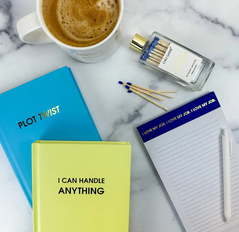 Notebooks, a cup of coffee, matches, and a bottle on a marble surface