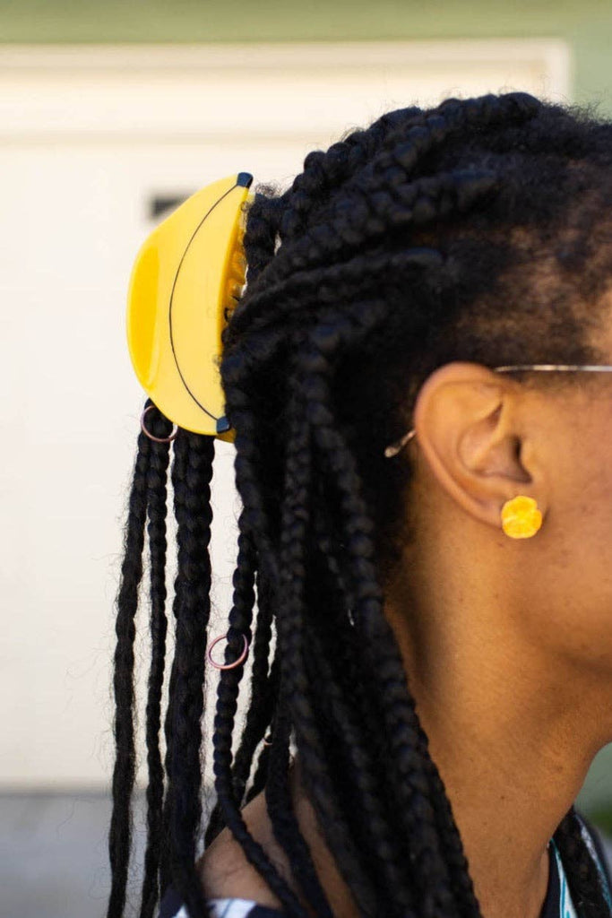 Woman with braided hair wearing a yellow  banana hair accessory 