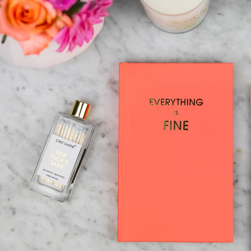 Candle with matches and 'Everything is Fine' notebook on a marble surface